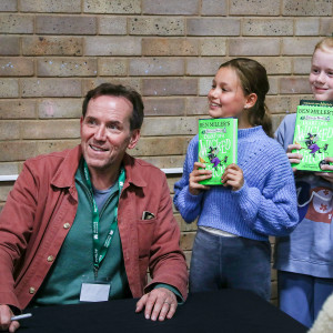 Ben Miller and three girls holding up books pose for a photo