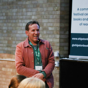 Ben Miller stands at the front of a town hall